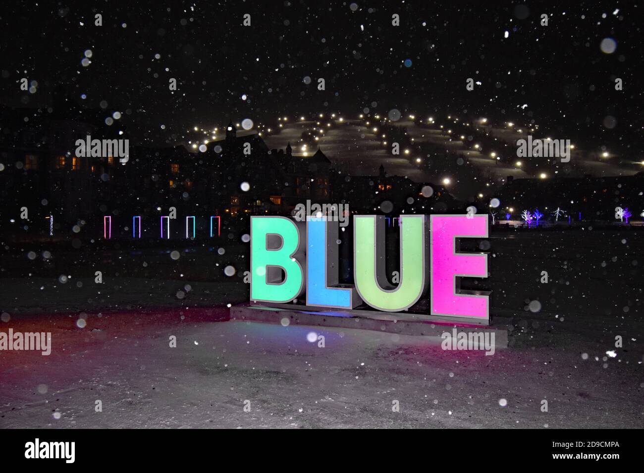 Blumination at the Blue Mountain Resort in Ontario, Canada.  A large illuminated sign reading BLUE stands infant of the ski slopes in the snow. Stock Photo