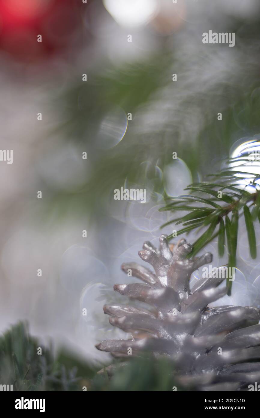 christmas decoration. close-up of a painted silver cone pine on a christmas tree. a red ball is on the left corner. Stock Photo