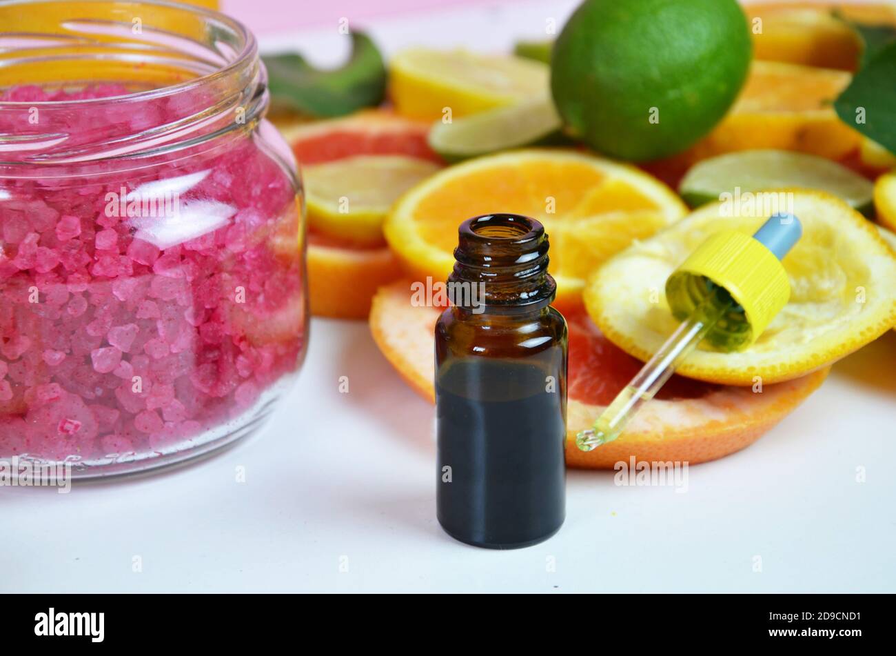beautiful spa composition Essential oil with citruses, pink sea salt for scrub. Aroma oil with citrus on white background Stock Photo