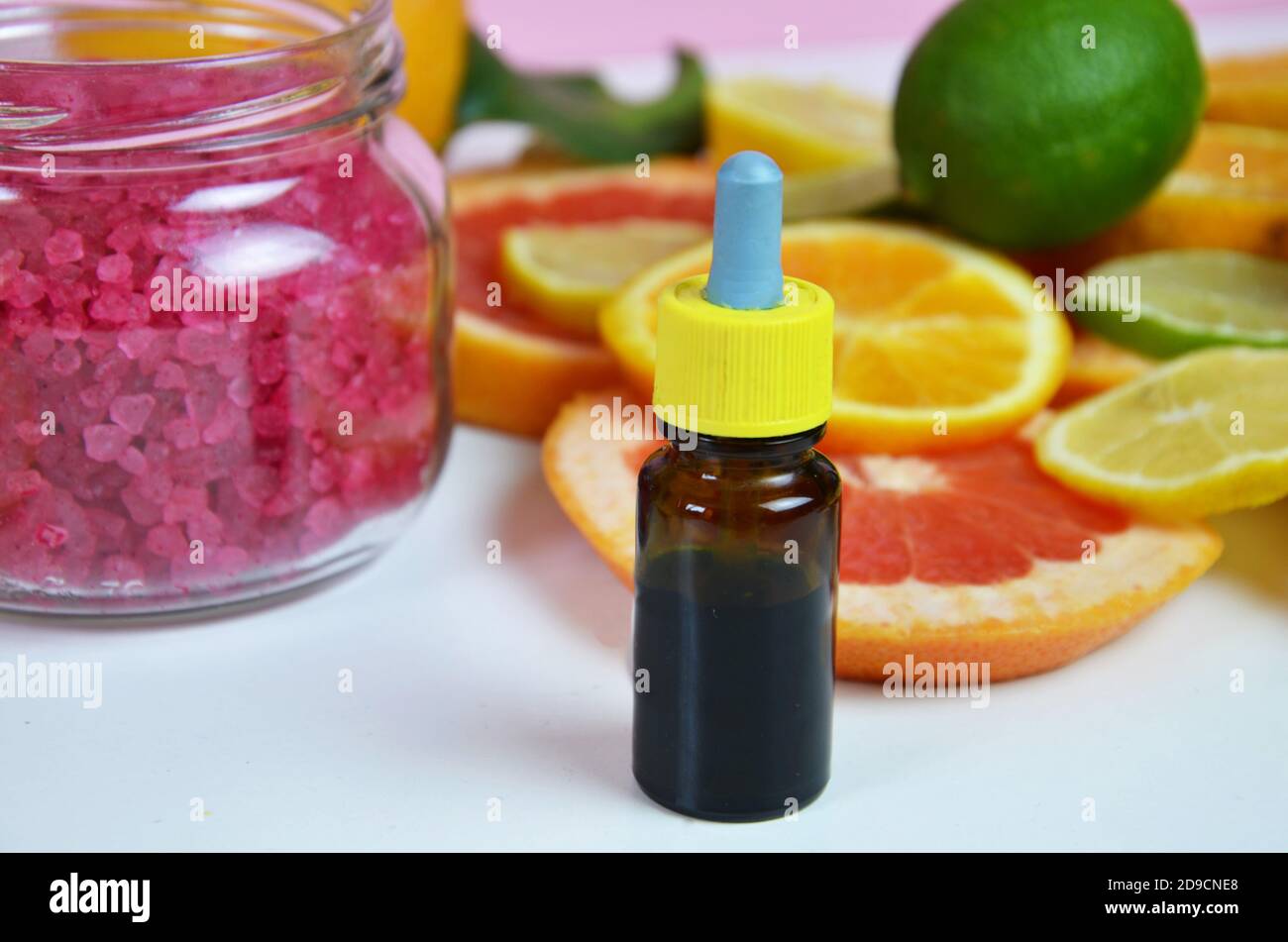 beautiful spa composition Essential oil with citruses, pink sea salt for scrub. Aroma oil with citrus on white background Stock Photo