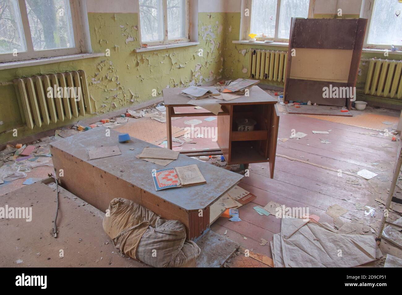 An abandoned kindergarten room in the Chernobyl exclusion zone. Old furniture. Shabby walls and a pile of rubbish on the floor. The interior of an aba Stock Photo