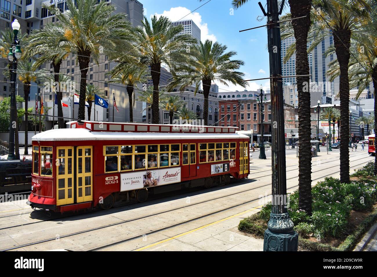 A traditional red and yellow streetcar on the Canal street line, New Orleans, Louisiana, USA. The wide street lined with palm trees & modern buildings. Stock Photo