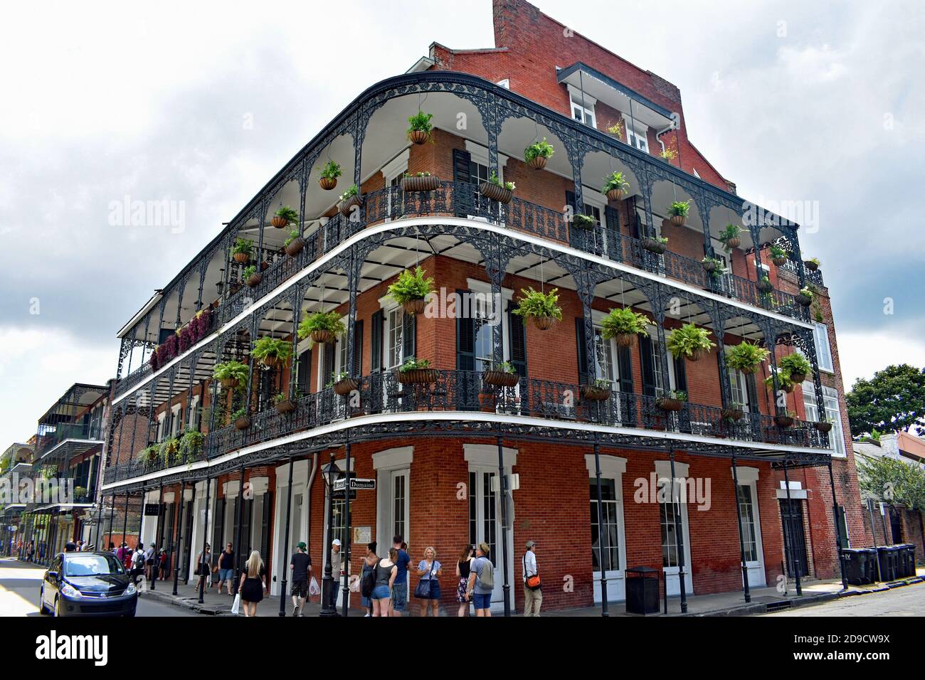 A traditional red brick building with ironwork galleries decorated with flowers and hanging baskets at Royal Street & Dumaine Street, New Orleans, USA Stock Photo