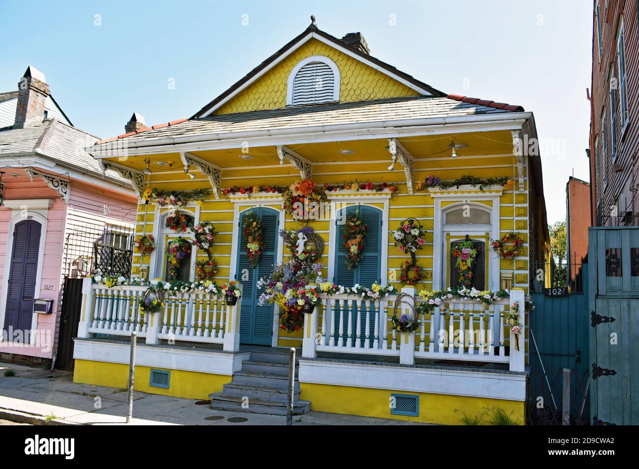 A traditional Creole cottage on St Ann Street in the historic French Quarter in New Orleans, Louisiana. The yellow house is decorated with flowers. Stock Photo