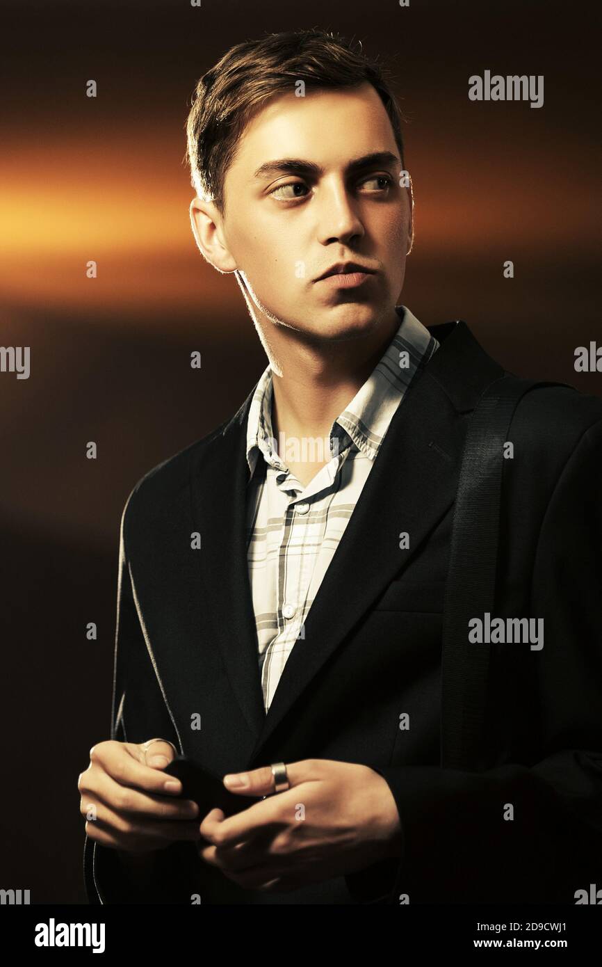 Young handsome man in black blazer walking on city street at night Stock Photo