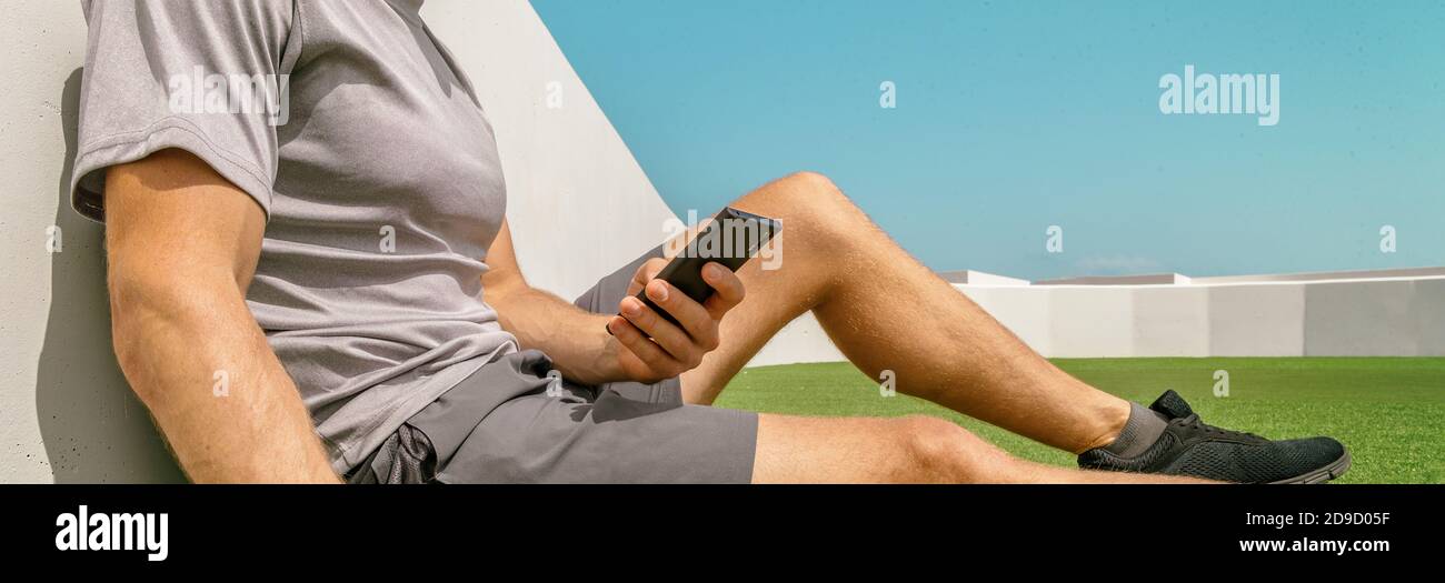 Phone app young fit guy active lifestyle panoramic banner. Athlete man relaxing texting on mobile smartphone outdoor at city park fitness gym Stock Photo
