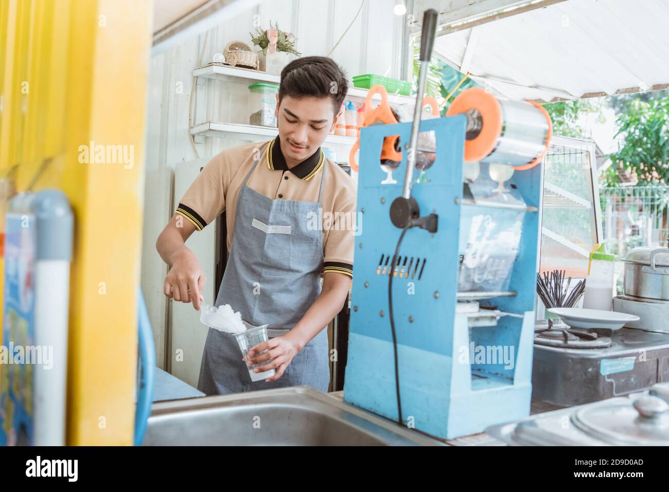 a man is pouring ice cube in the plastic glass. small shop seller Stock Photo
