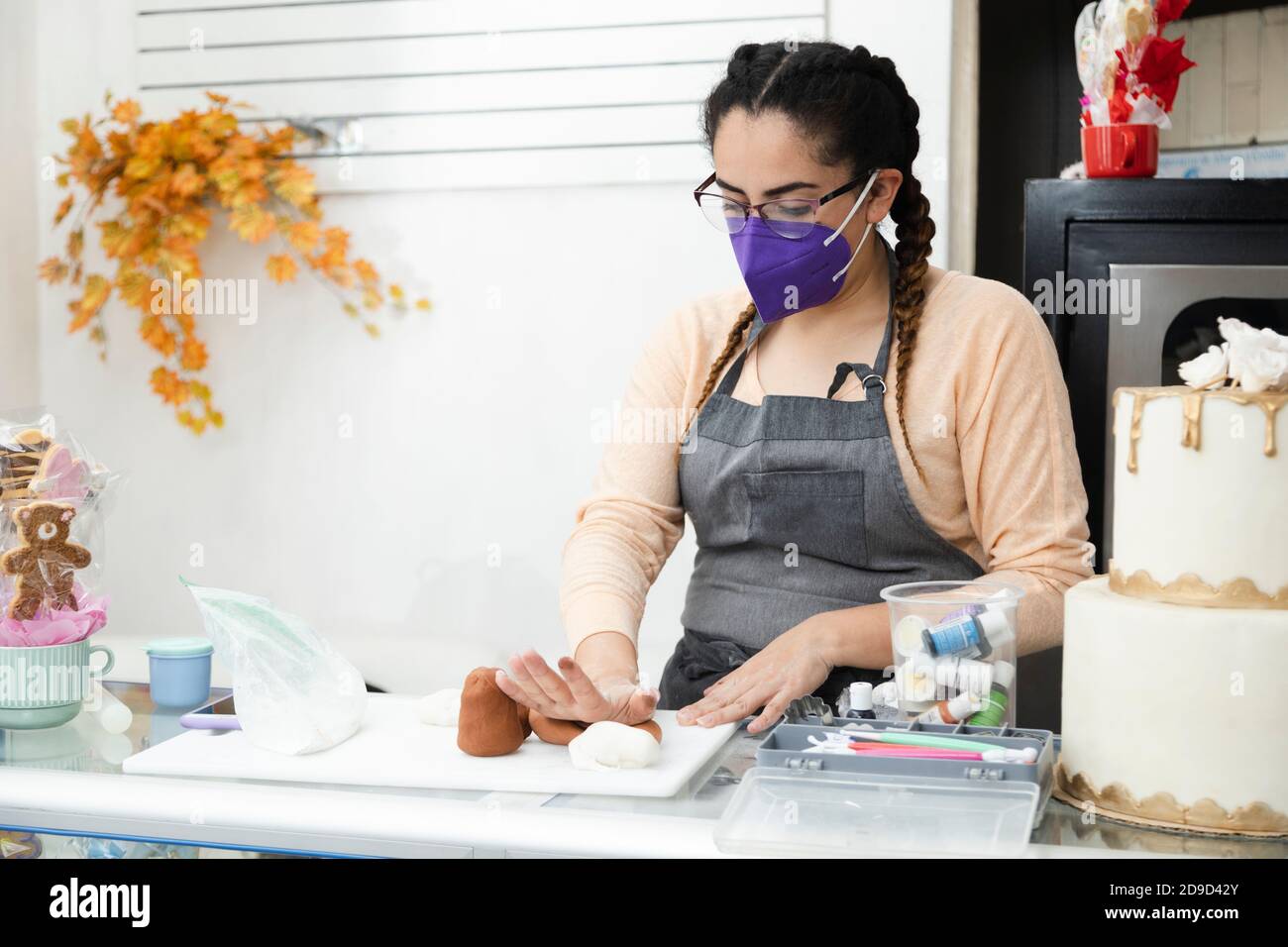 Young pastry chef working with mask - Hispanic pastry chef working with fondant - enterprising woman Stock Photo