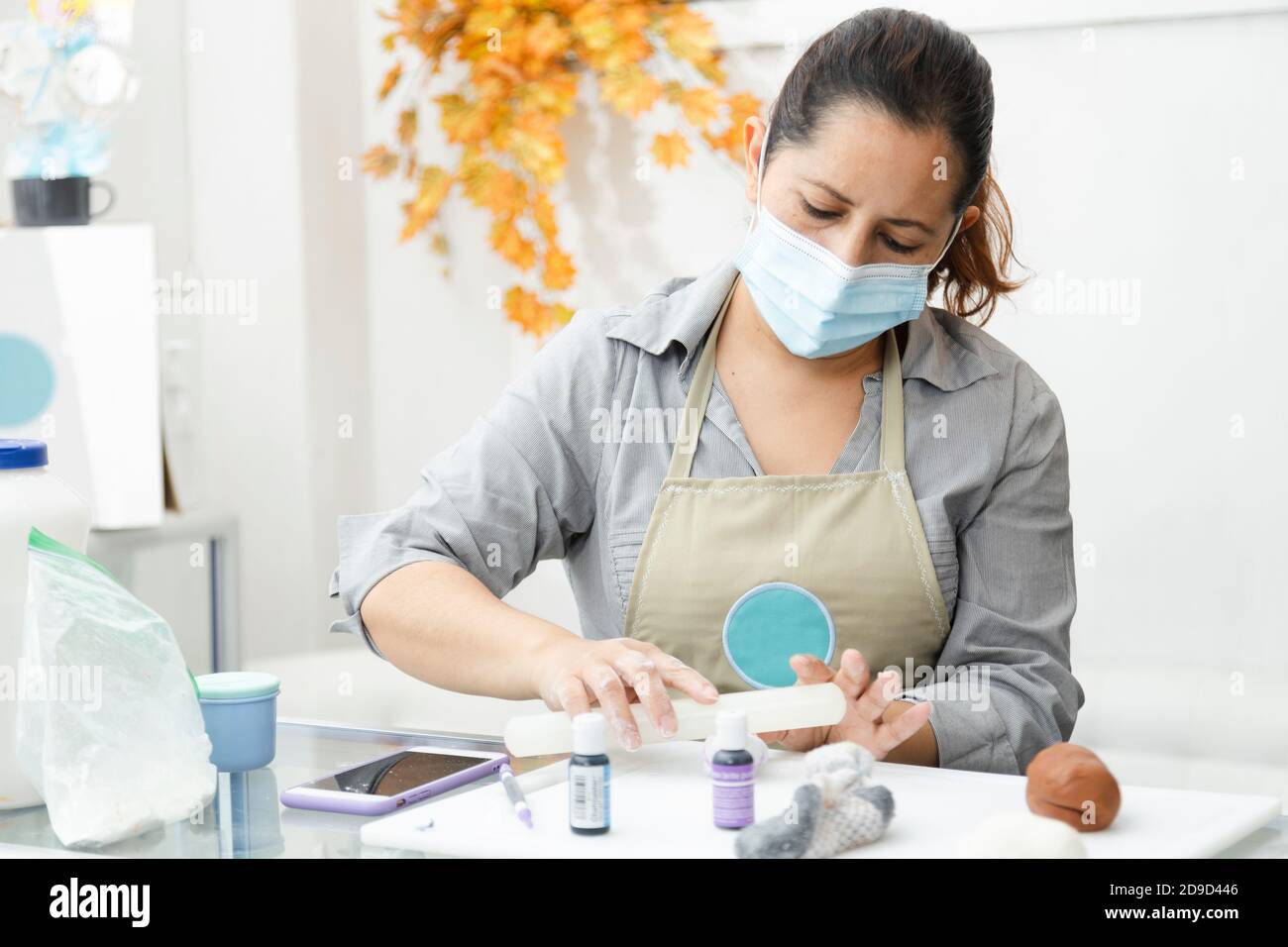 Pastry chef working with fondant to decorate a cake - Woman cooking with mask - Woman painting clay with dyes Stock Photo