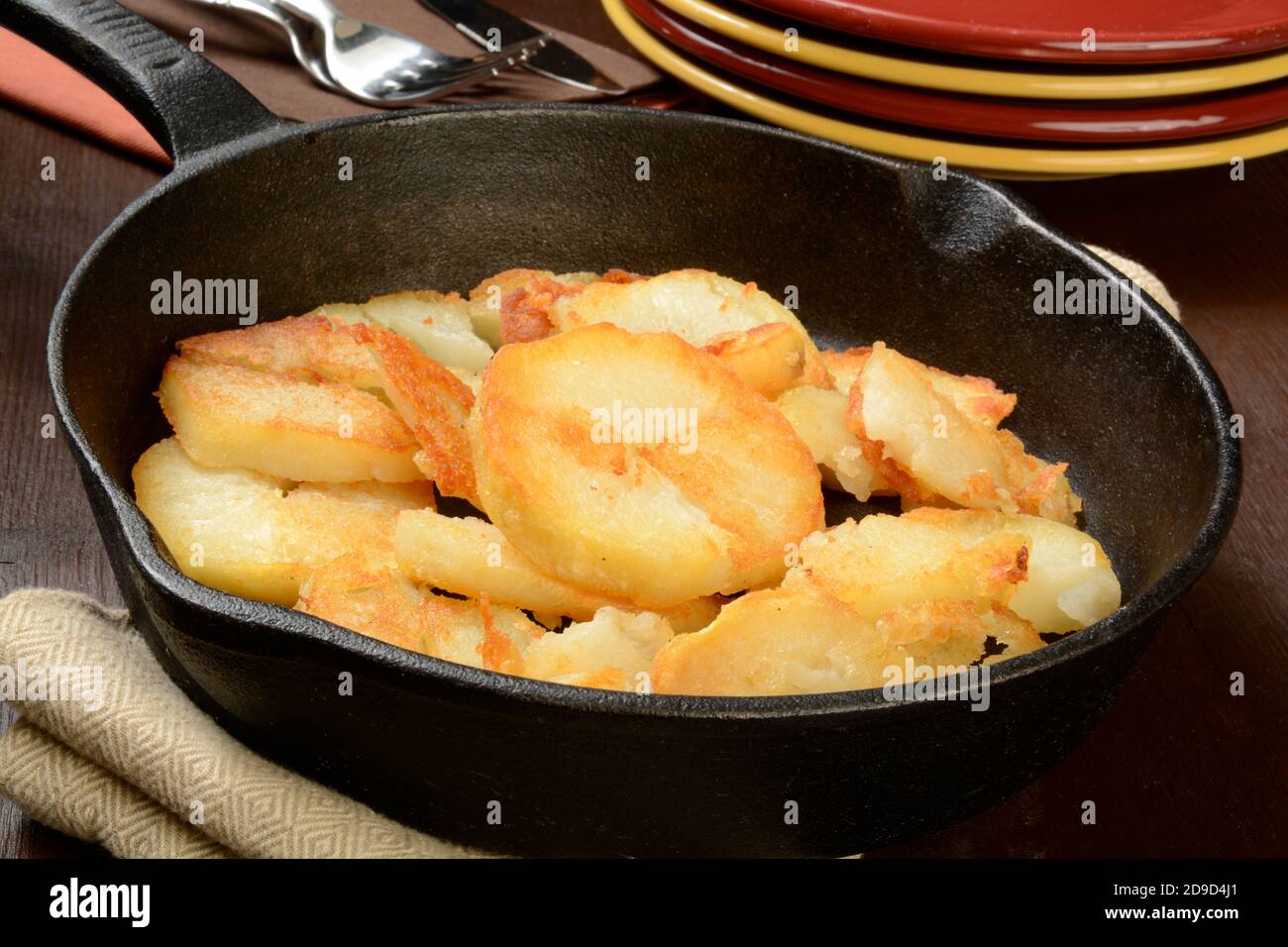 Home fried potatoes iln a cast iron skillet with serving plates Stock Photo  - Alamy