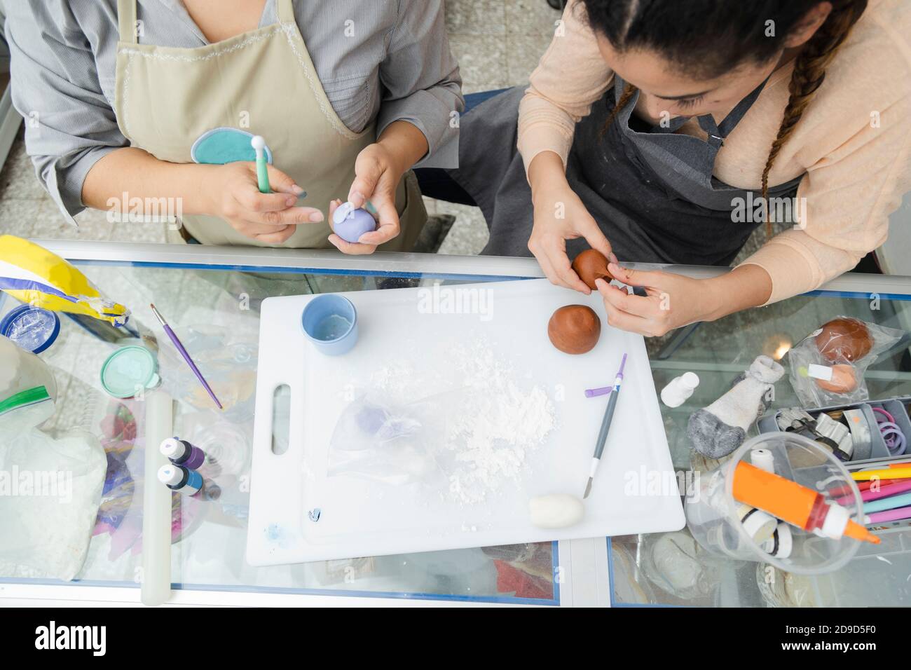 Top view of the hands of women pastry chefs working with fondant to decorate a cake - hands molding clay with tools and coloring - women artisans Stock Photo