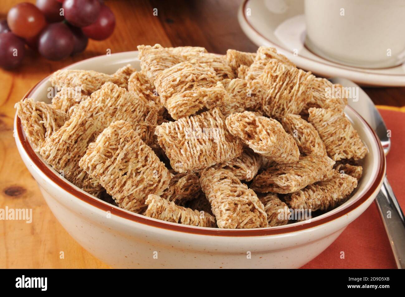 A bowl of shredded organic wheat biscuits with a cup of coffee Stock