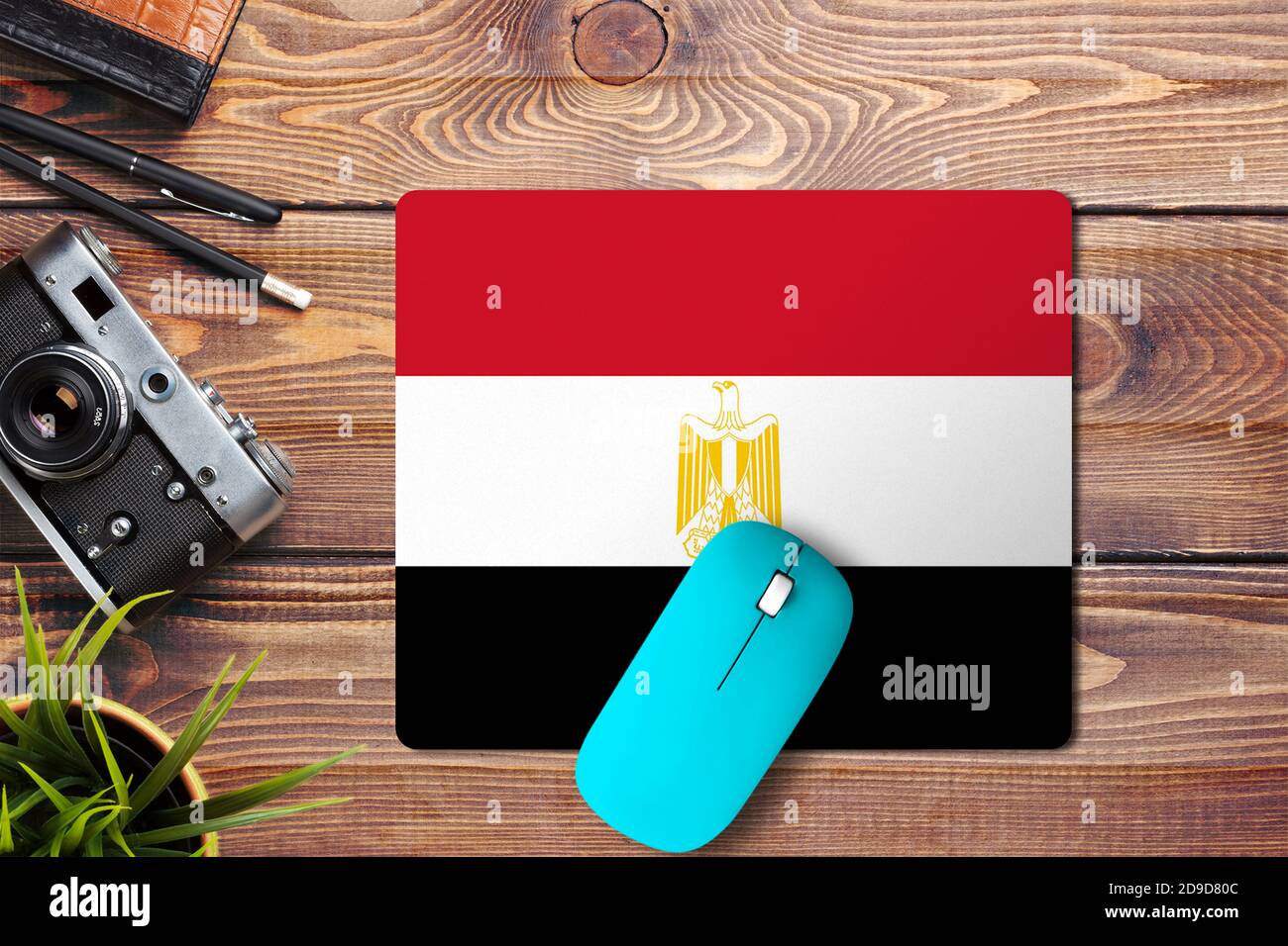 Egypt flag on wooden background with blue wireless mouse on a mouse pad