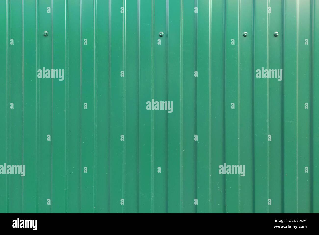 The green fence of sheet corrugated iron is attached to the bolts. Background for text and design. Stock Photo