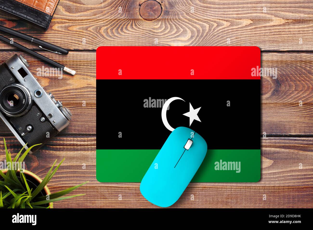 Libya flag on wooden background with blue wireless mouse on a mouse pad,  top view. Digital media concept Stock Photo - Alamy