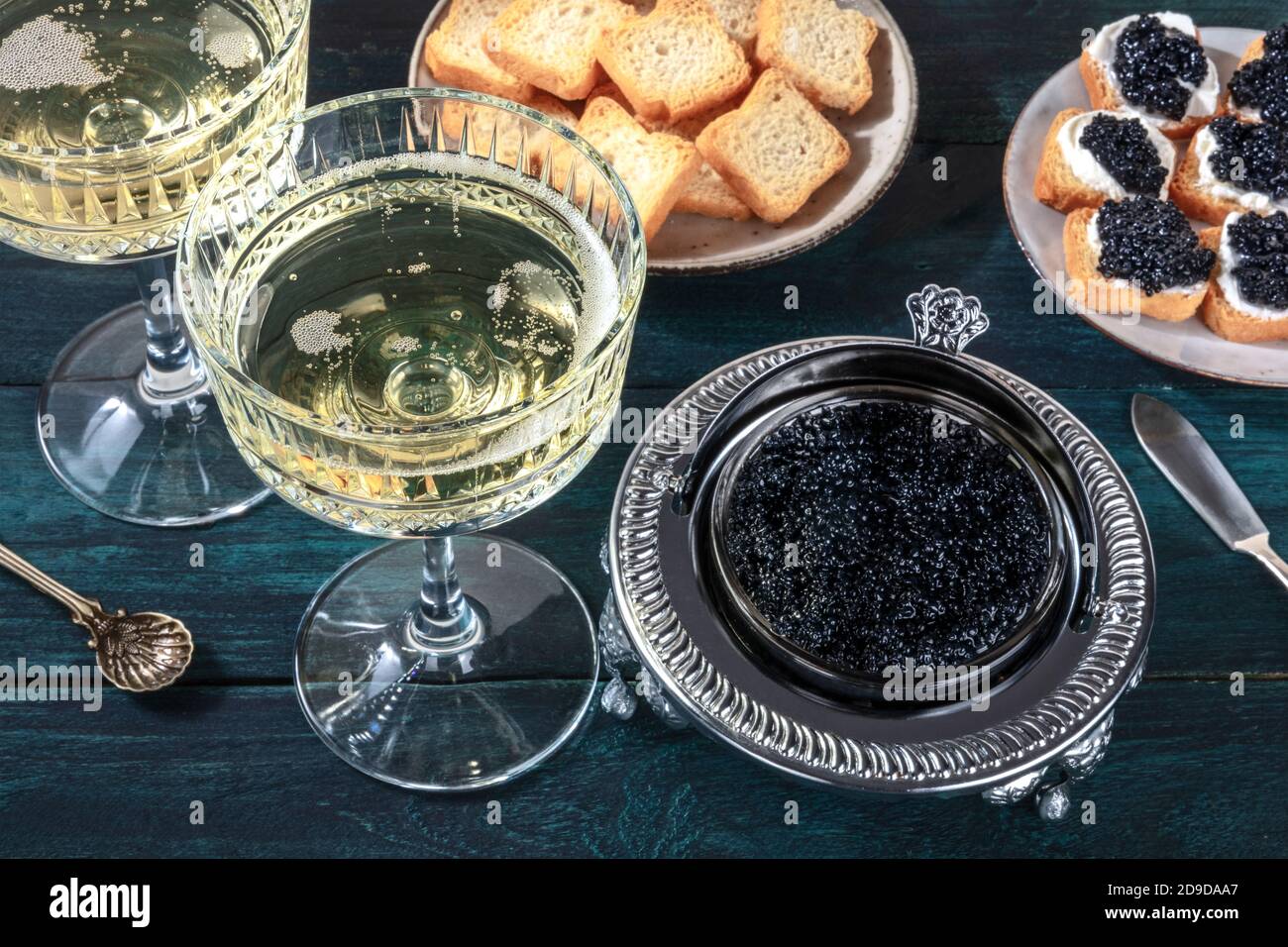 Caviar and champagne, vintage style, with bread and toasts on a dark blue wooden background Stock Photo