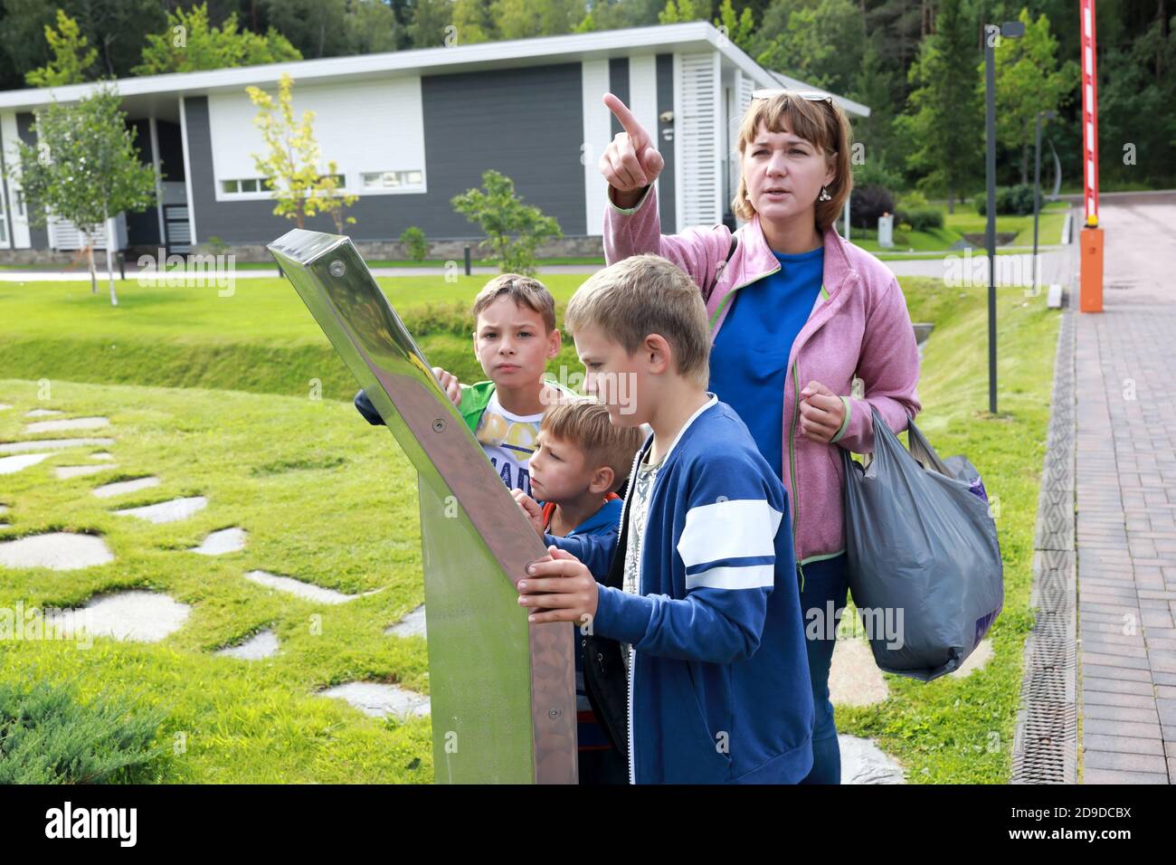 Mother and sons look at map of park in summer Stock Photo