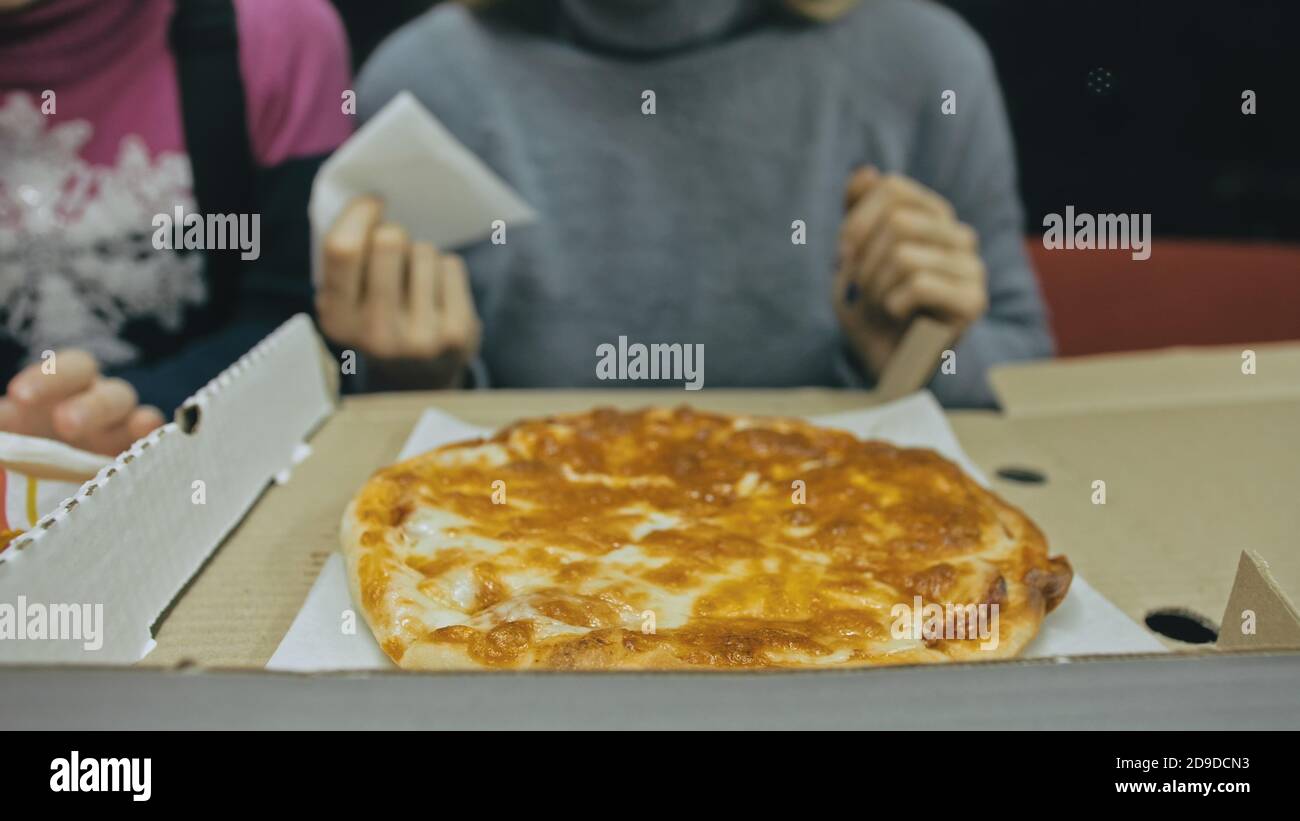 Girl eat pizza cheese four. Close up of young woman mouth greedily eating pizza and chewing in outdoor restaurant. Junk food. Pizza from open box. Stock Photo