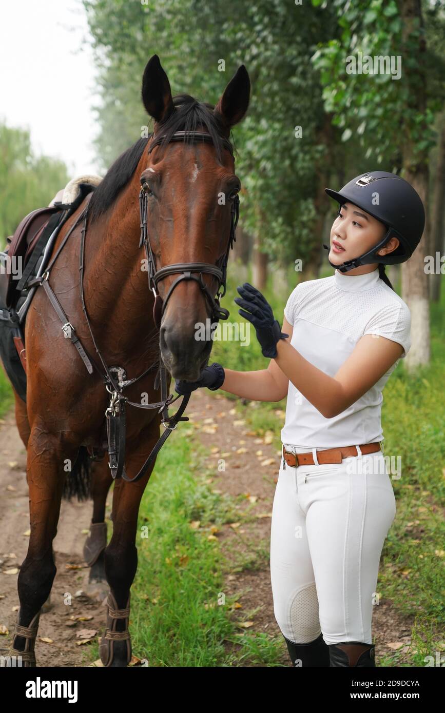 Outdoor young female riders checking their horses Stock Photo - Alamy