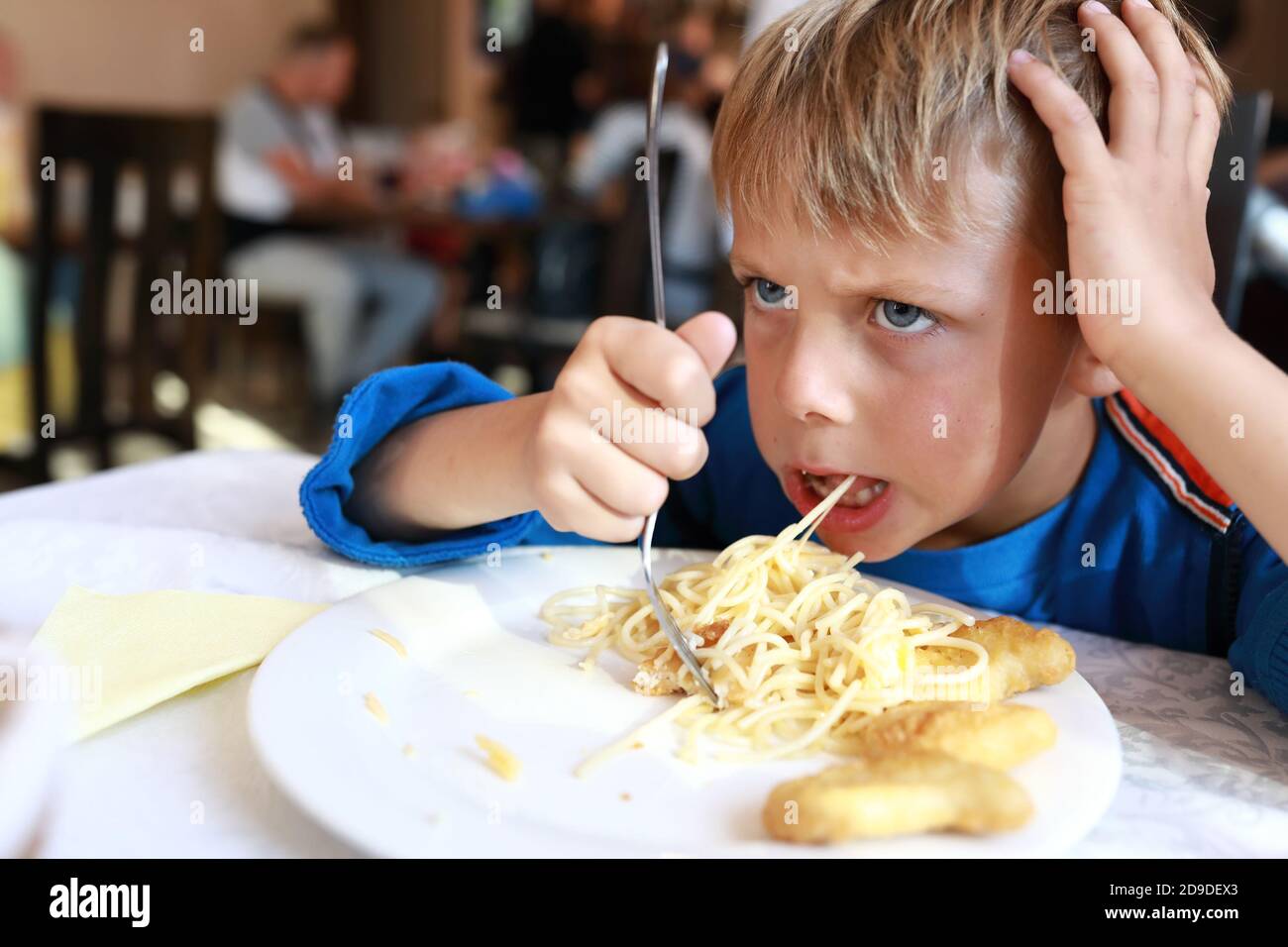 Kid has spaghetti with nuggets in restaurant Stock Photo