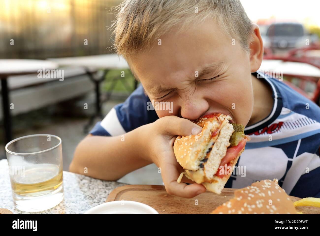 Kid eating burger in an outdoor restaurant Stock Photo