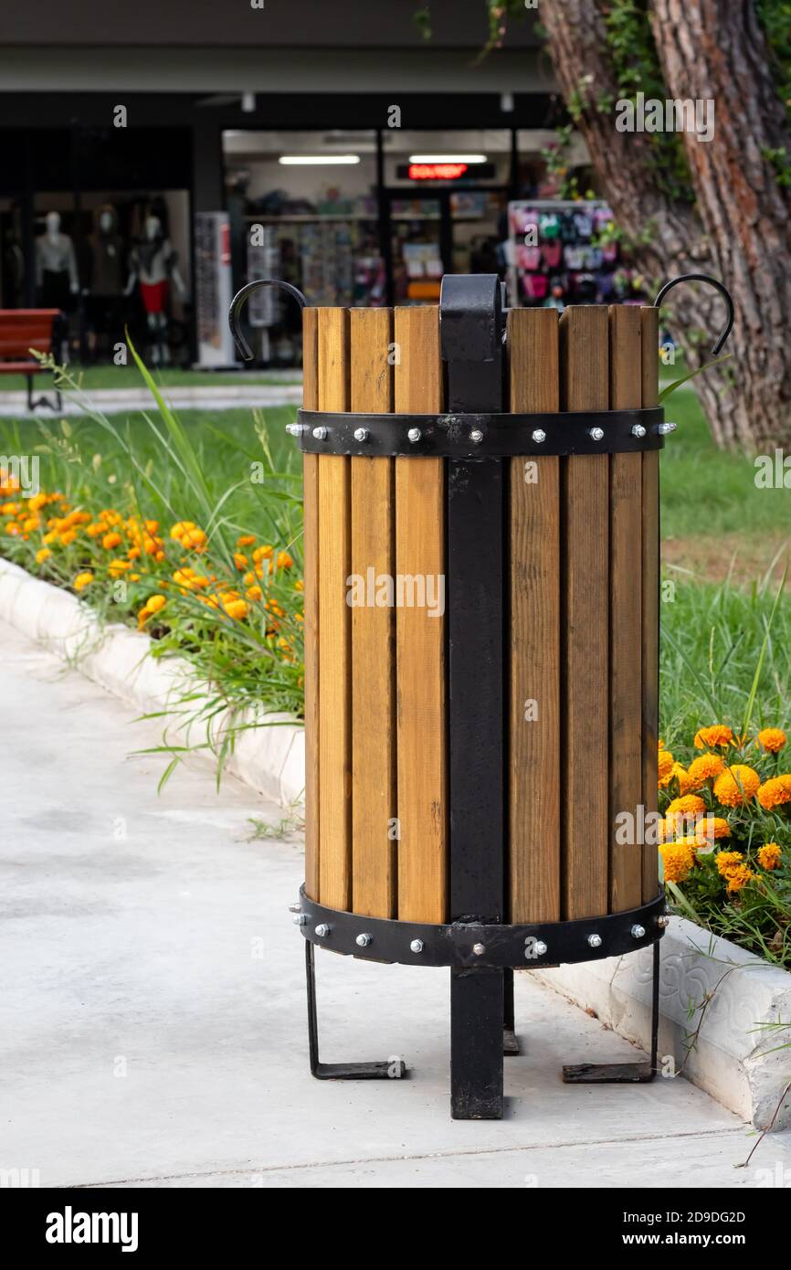 Rubbish bin in the park in summer. Turkish wooden trashcan outdoor, urn for garbage, wastebasket and grass with flowers Stock Photo