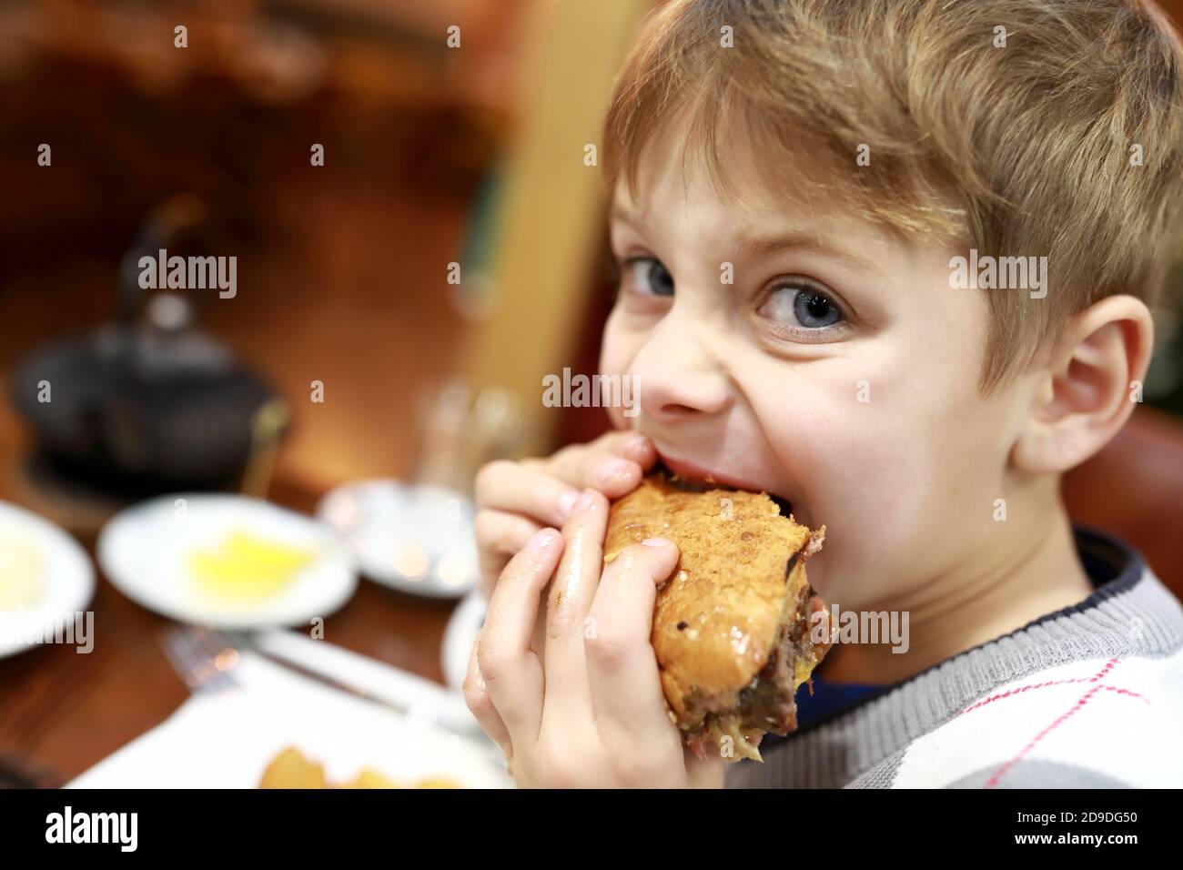 Portrait of kid eating burger in restaurant Stock Photo