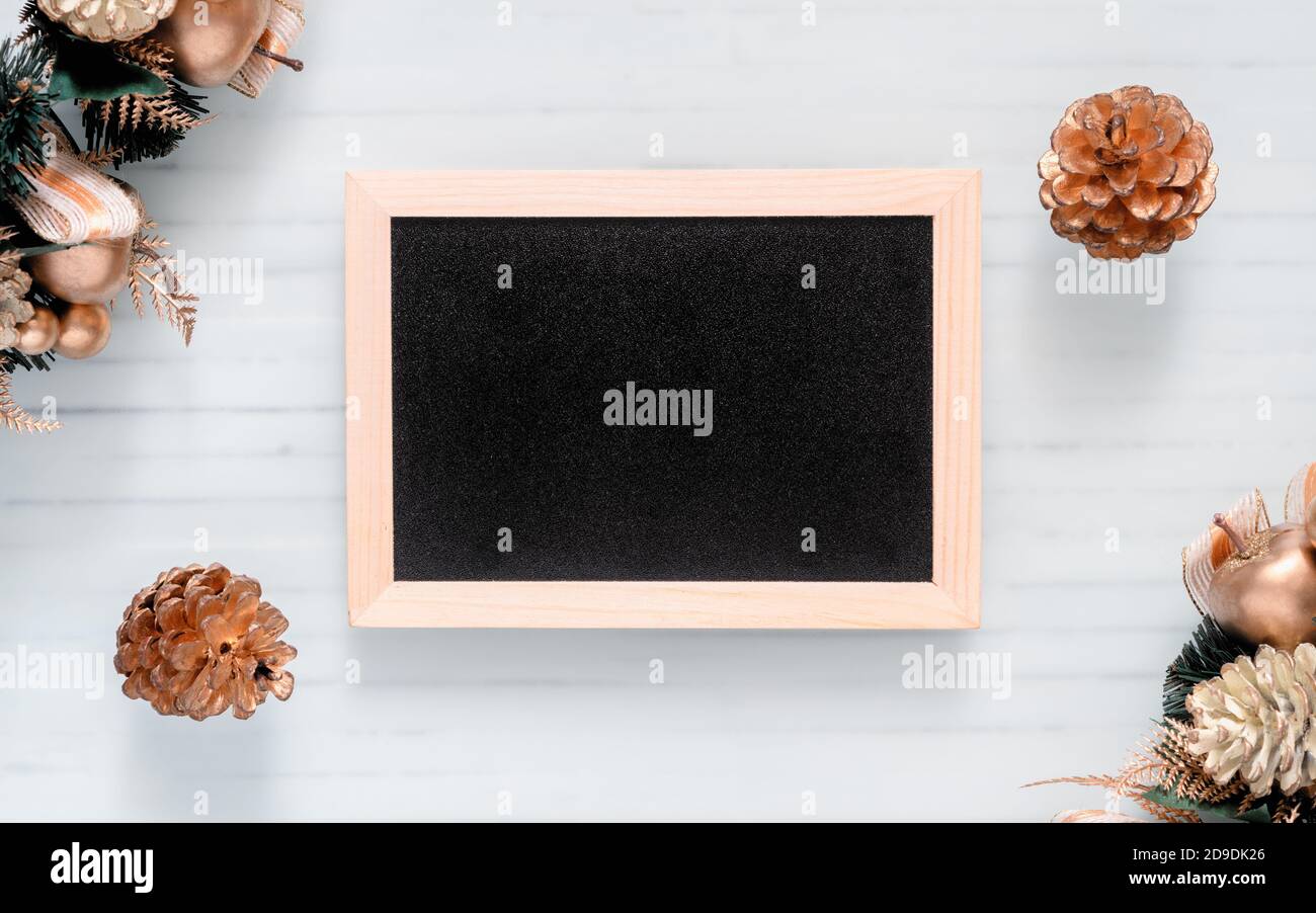 Mockup chalkboard with blank empty screen, new year gift box with Xmas pine tree model, christmas ornaments on white wood desk, top view, copy space p Stock Photo
