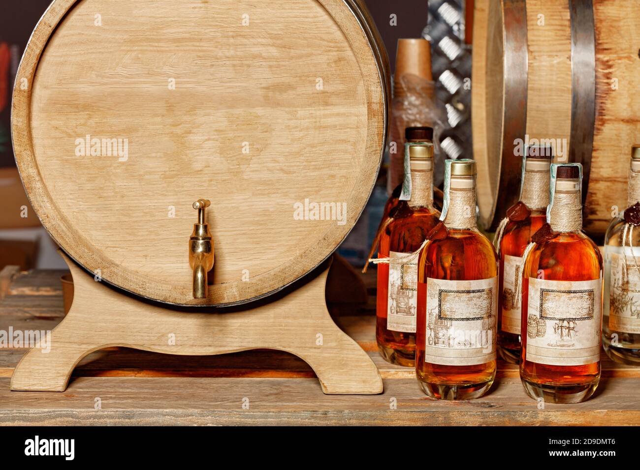 Front view of an oak barrel with a brass tap and sealed liquor bottles