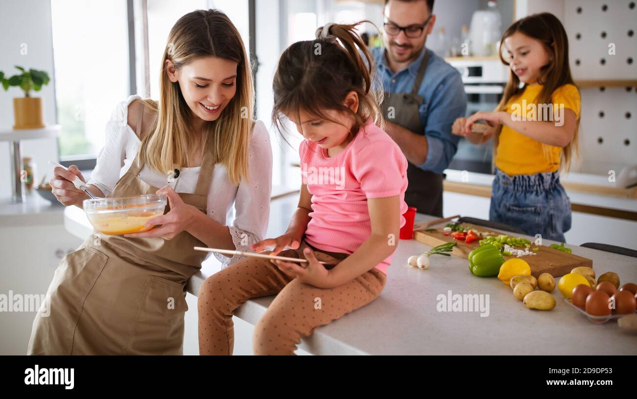 Overjoyed young family with kids having fun, cooking at home together Stock Photo