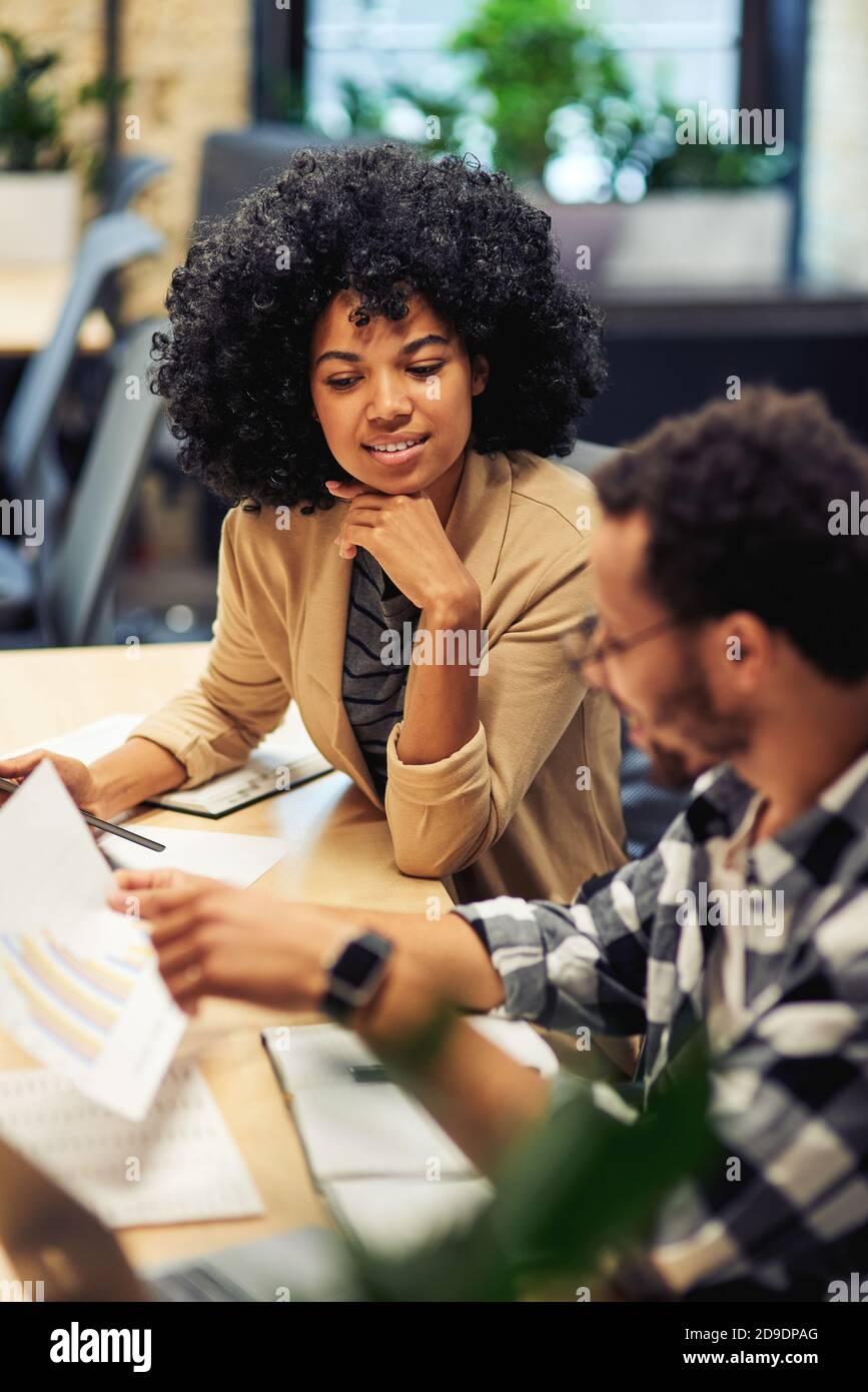 Two young diverse coworkers analyzing sales report while working together in the office. Business and teamwork concept Stock Photo