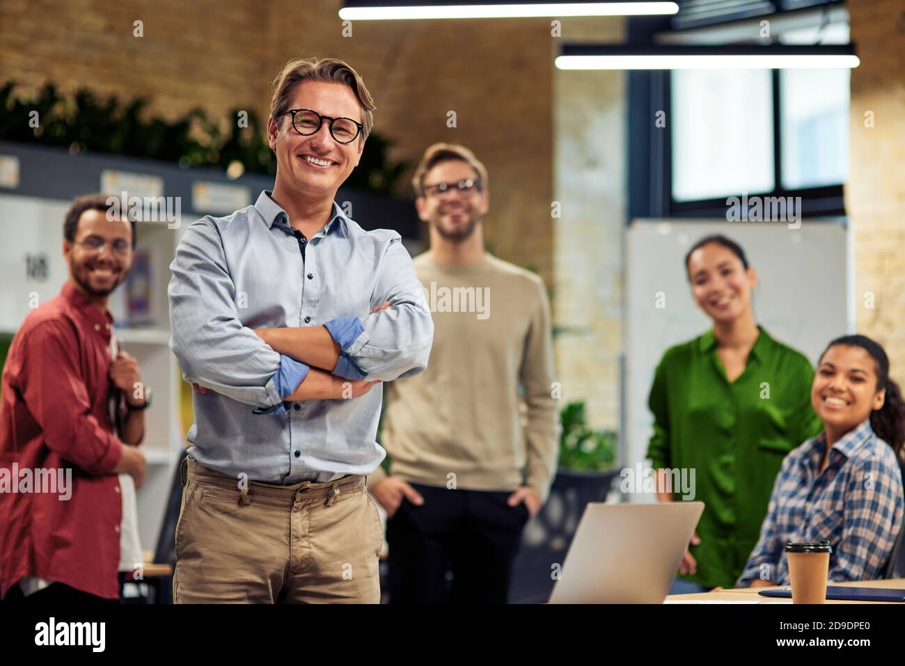 Happy startup team. Group of cheerful multiracial business people smiling at camera while standing in the modern office, working together. Collaboration and cooperation concept Stock Photo