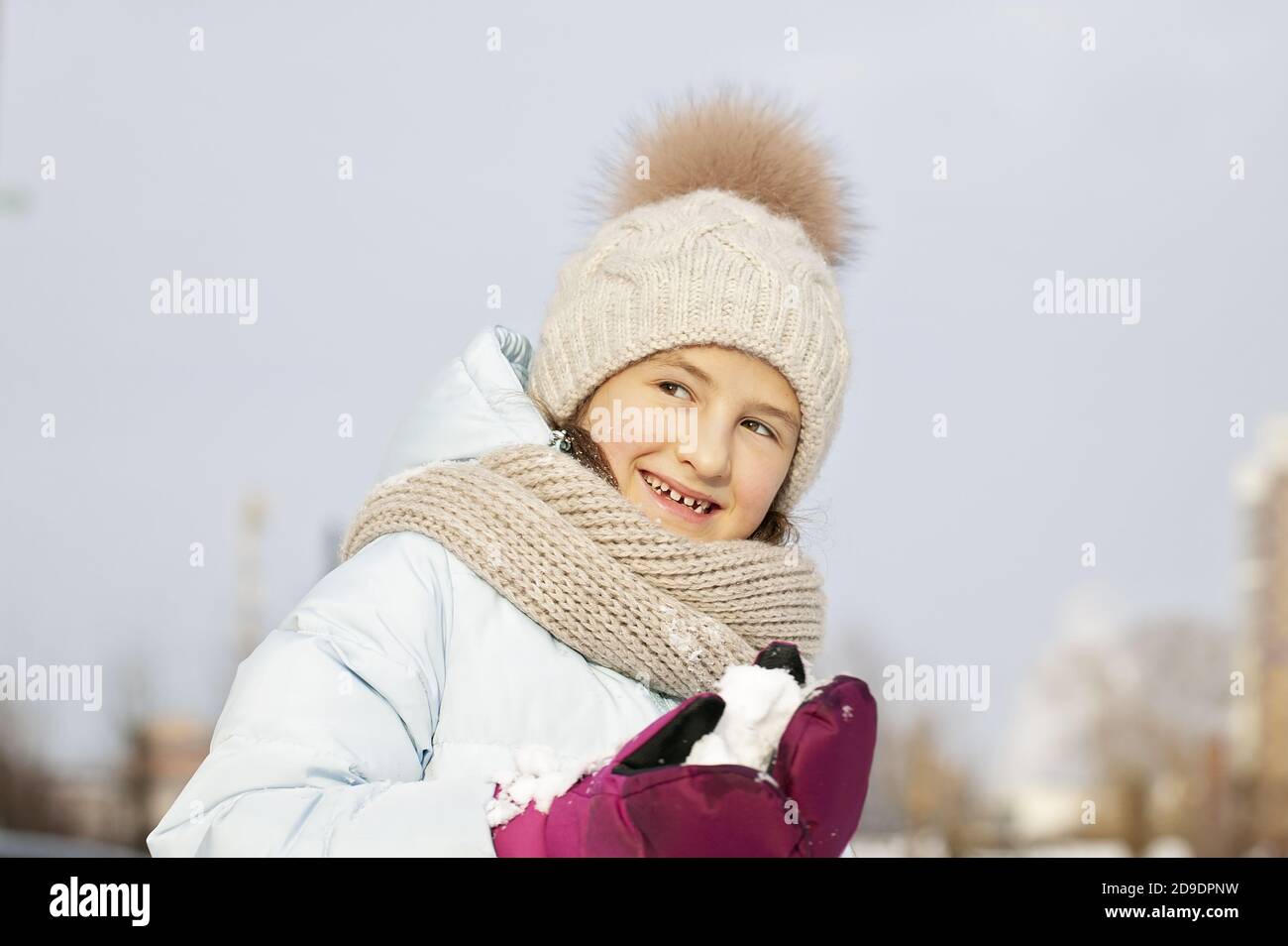 Winter portrait of a happy beautiful girl in a winter knitted hat. Girl holding snow. Lifestyle Stock Photo