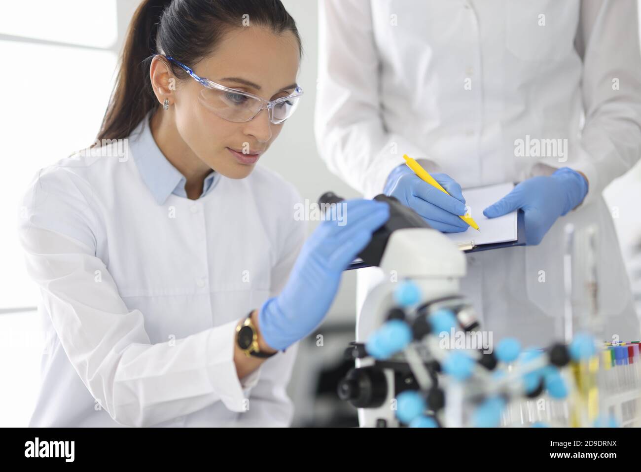 Researcher and colleague are conducting research in laboratory under ...