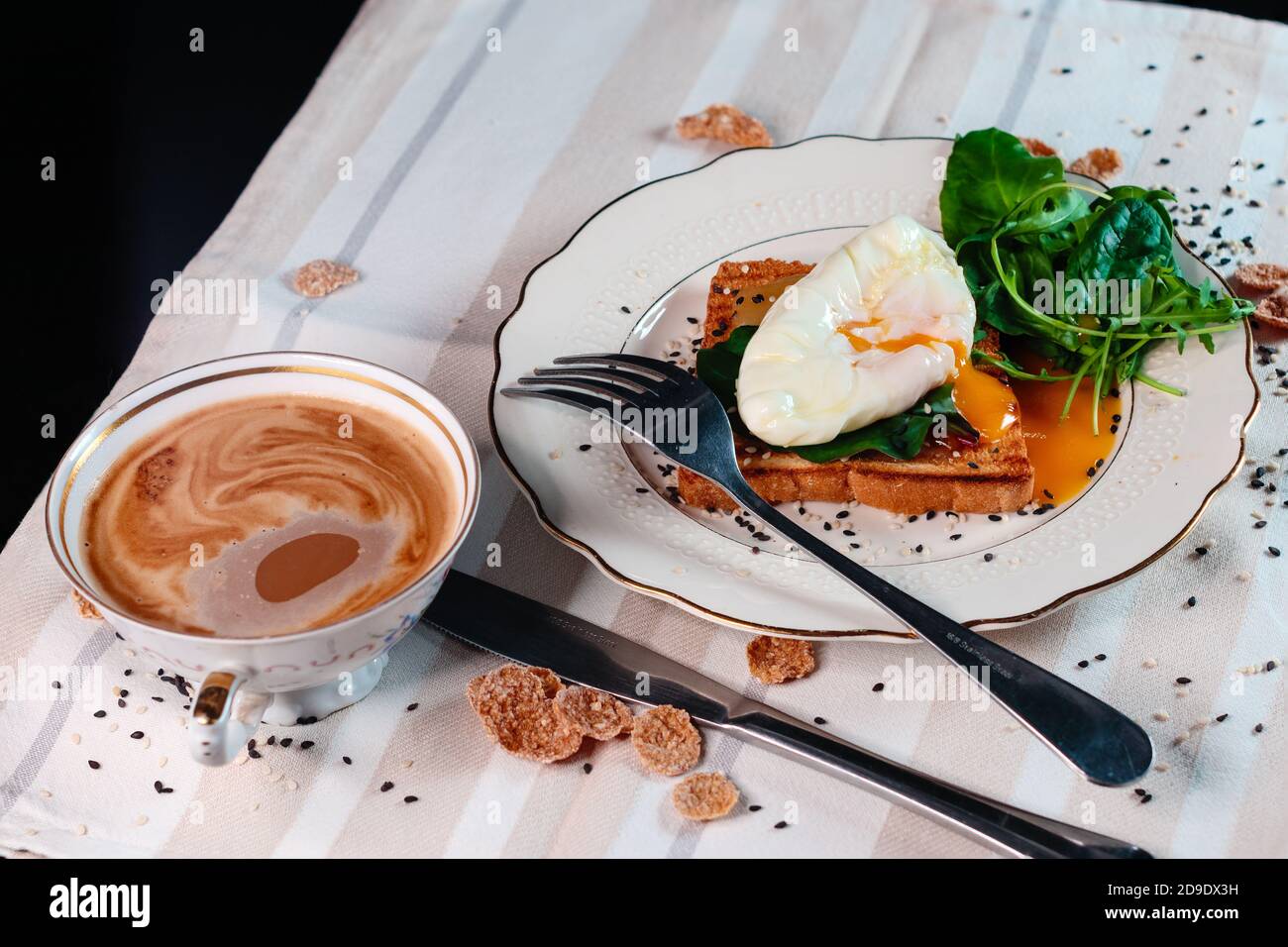 Healthy breakfast with poached egg on toast with green salad leaves. Egg yolk spread Stock Photo