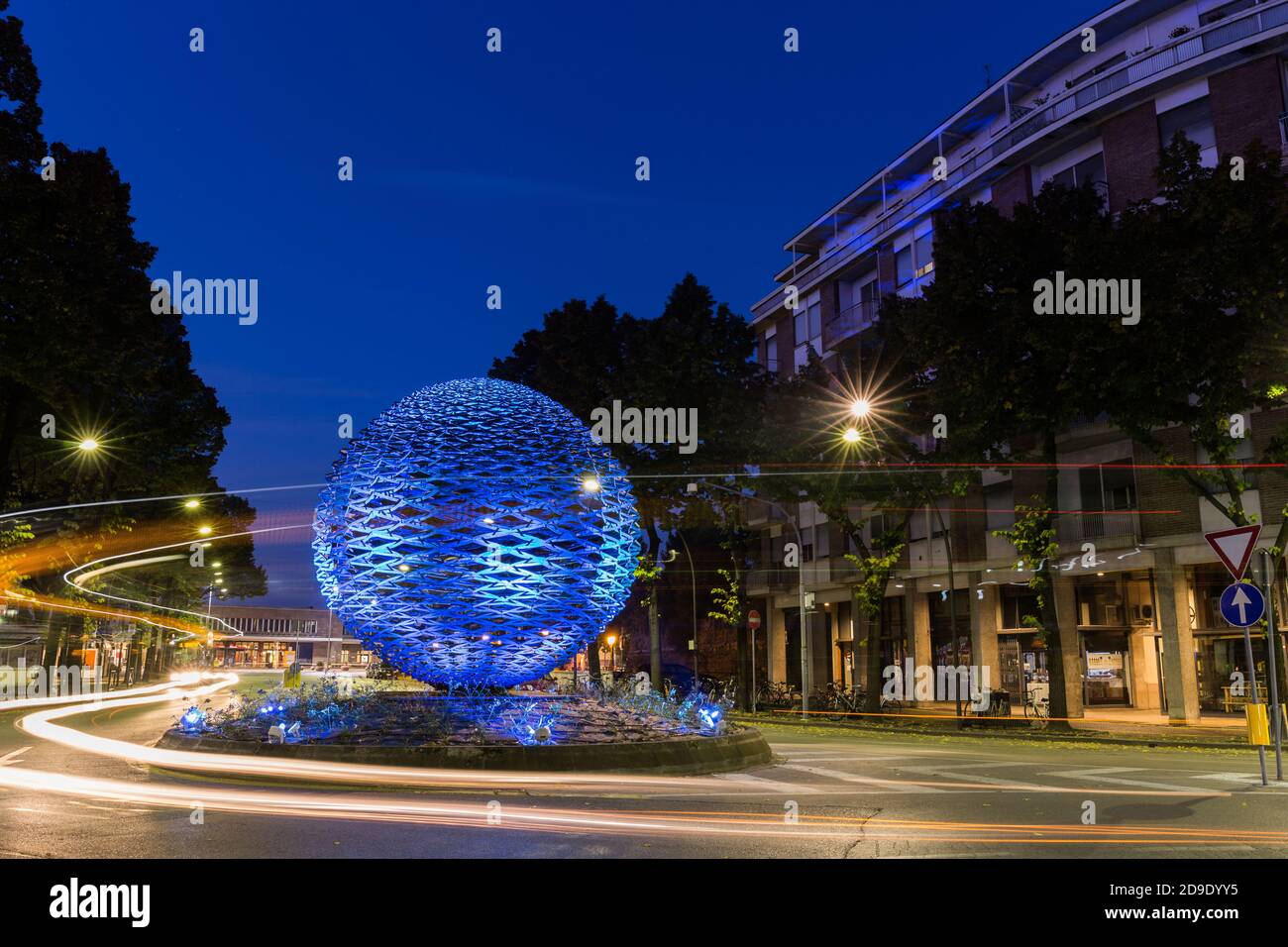Large decorative illuminated in blue ball on a road with beautiful car lights at night. Treviso Italy Stock Photo