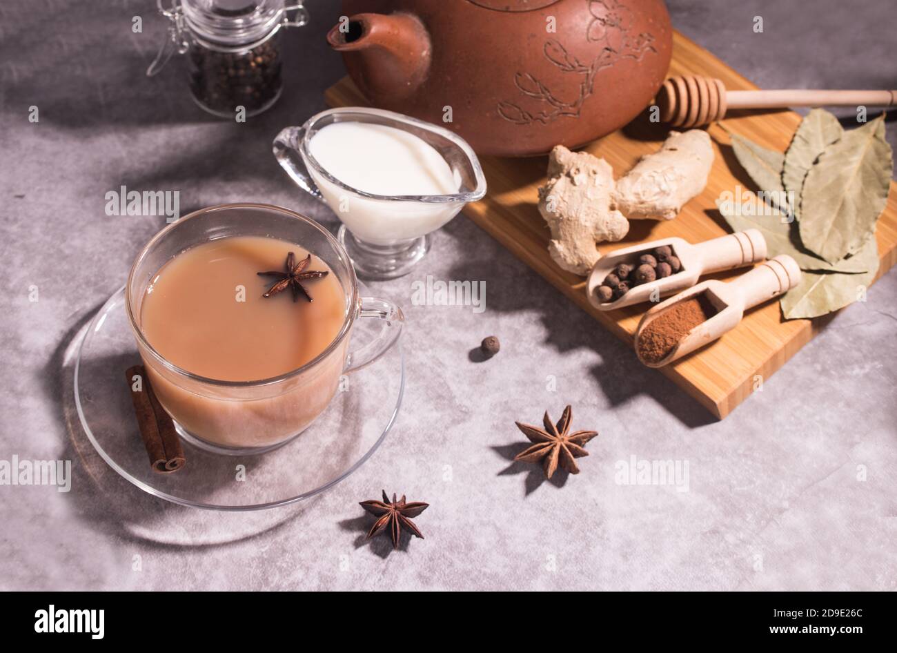 A Cup of hot Indian tea masala tea, milk jug, teapot and spices on a gray background. Horizontal orientation. Stock Photo