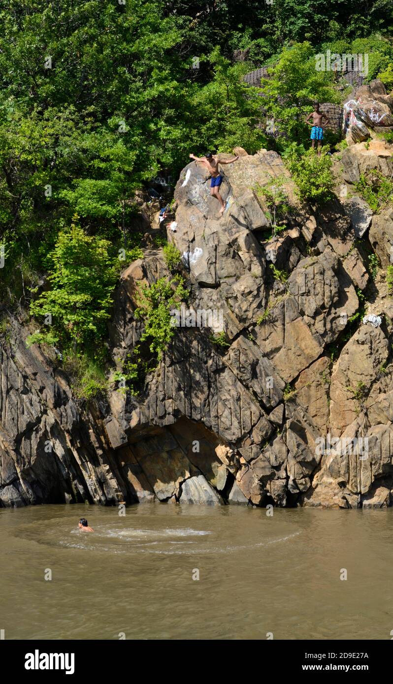 New York, Bronx, Hudson River, boys cliff jumping (frame1) at Jungle and Capone’s Chair at Spuyten Duyvil Creek. Viewed from Circle Line tourist boat. Stock Photo