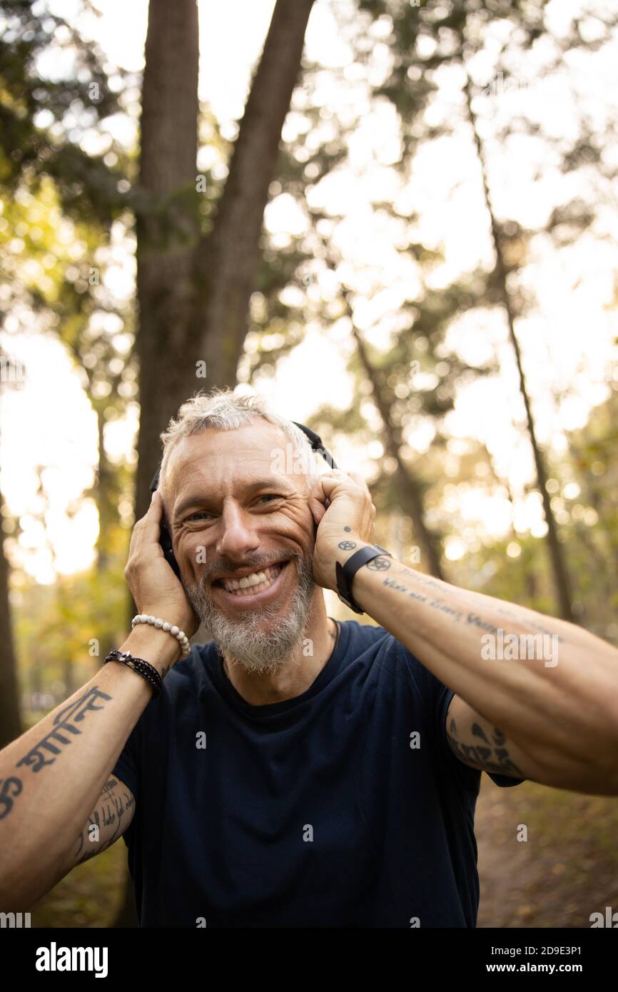 Joyful man in earphones running in forest Stock Photo