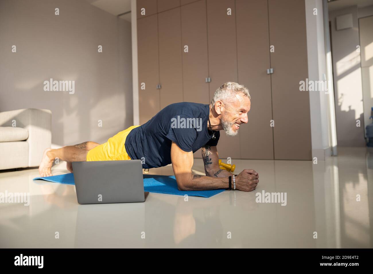 Excited male doing a front hold in a sunny room Stock Photo