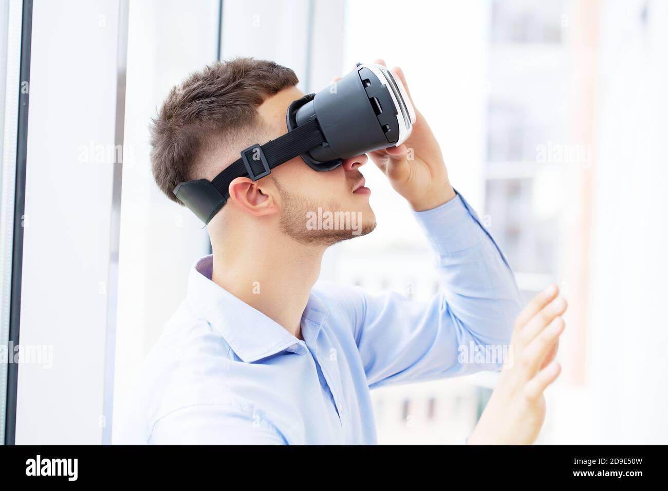 Young man wearing virtual reality glasses in modern office Stock Photo ...