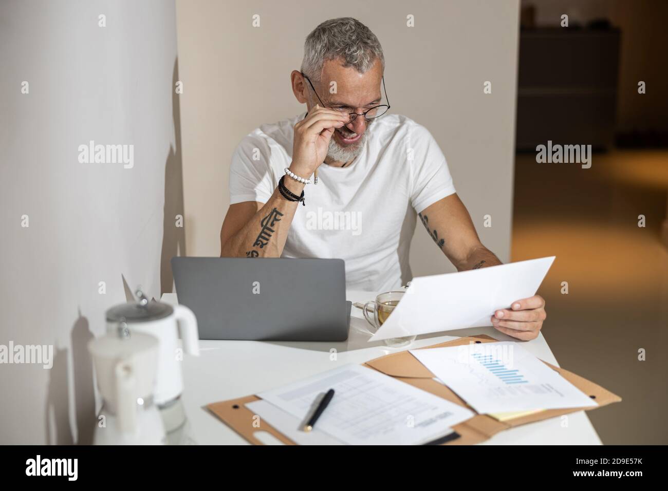 Man adjusting his glasses while checking a document Stock Photo