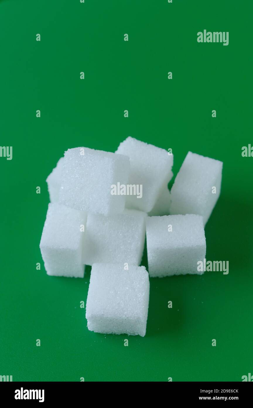 Cube of white and brown sugar on a green background. Green screen background. Stock Photo