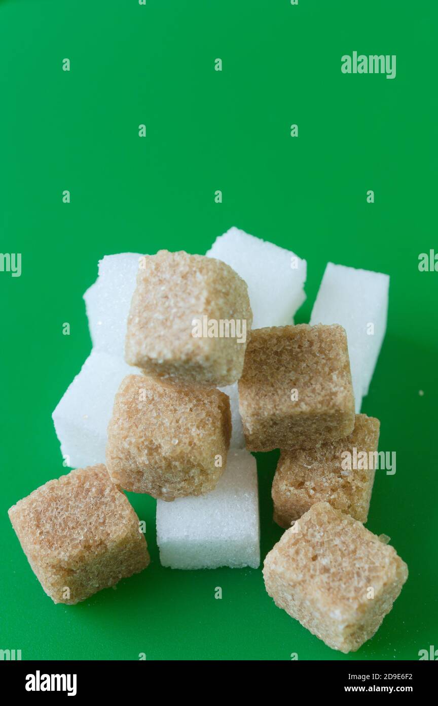 Cube of white and brown sugar on a green background. Green screen background. Stock Photo