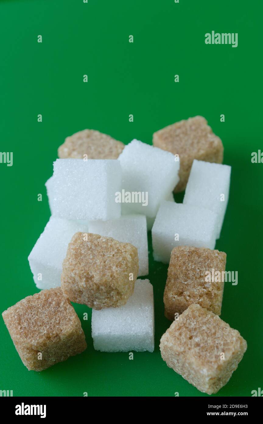 Cube of white and brown sugar on a green background. Green screen background. Stock Photo