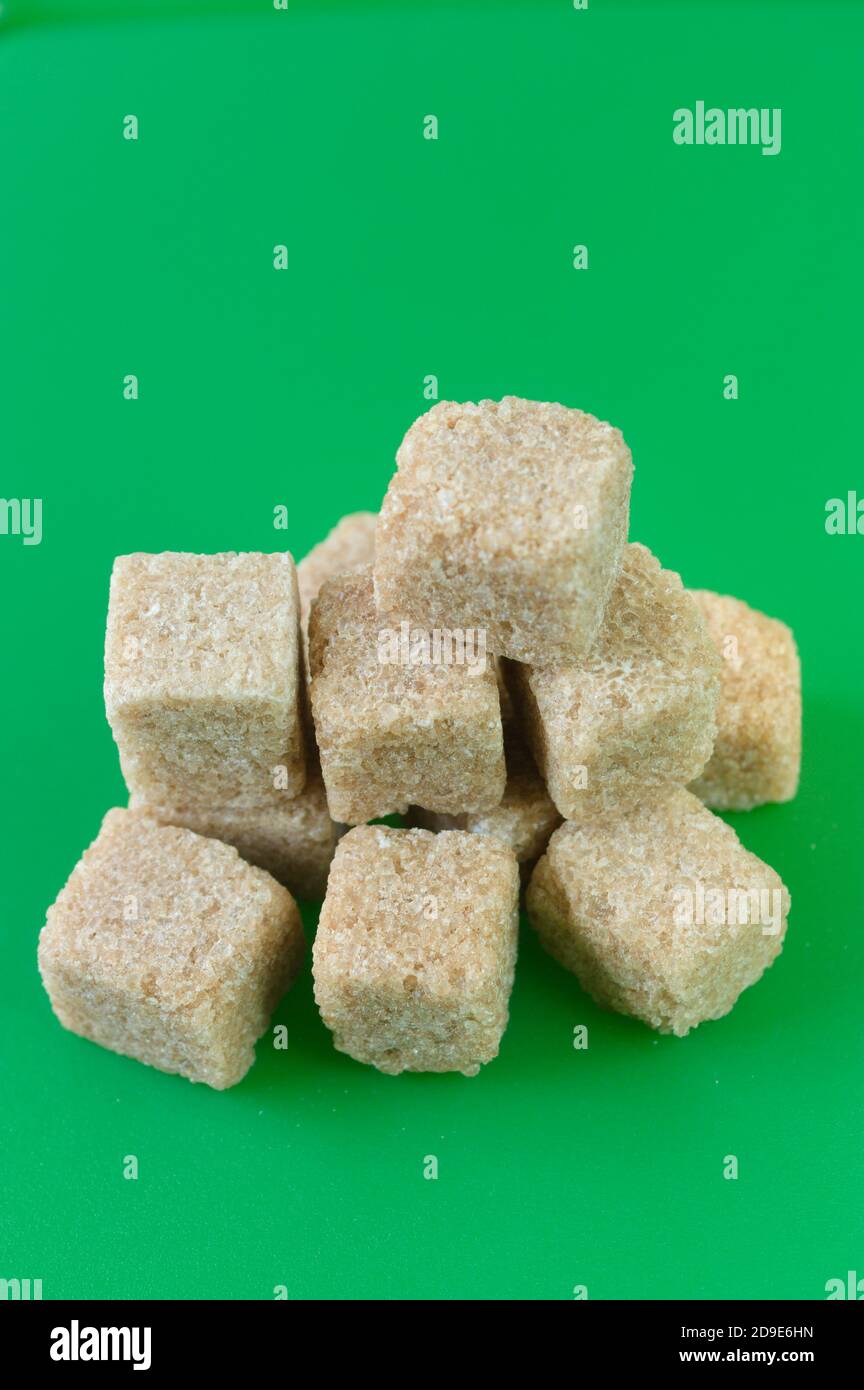 Cube of white and brown sugar on a green background. Green screen background. Stock Photo