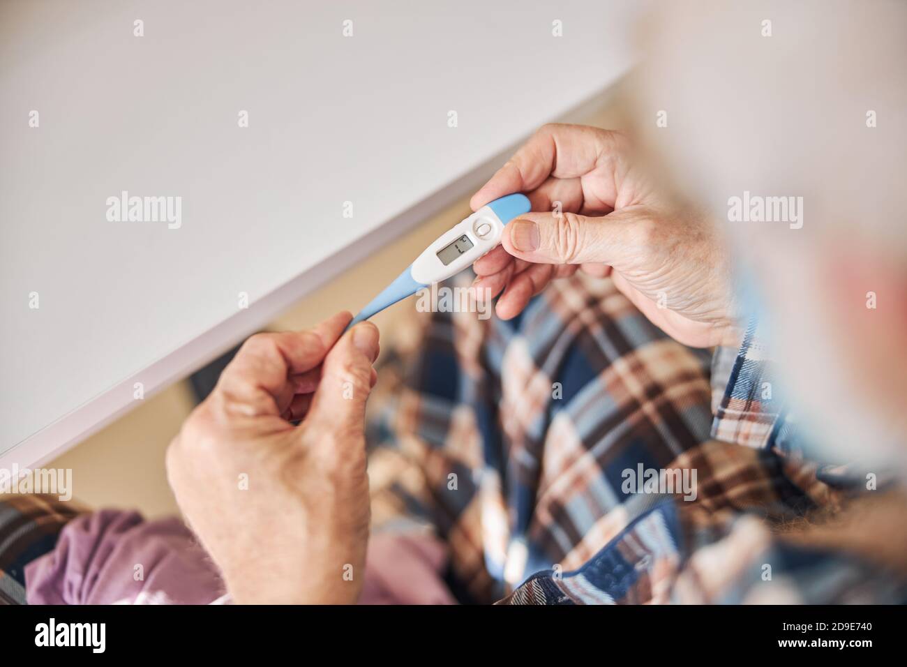 Aged man using a temperature measuring device Stock Photo
