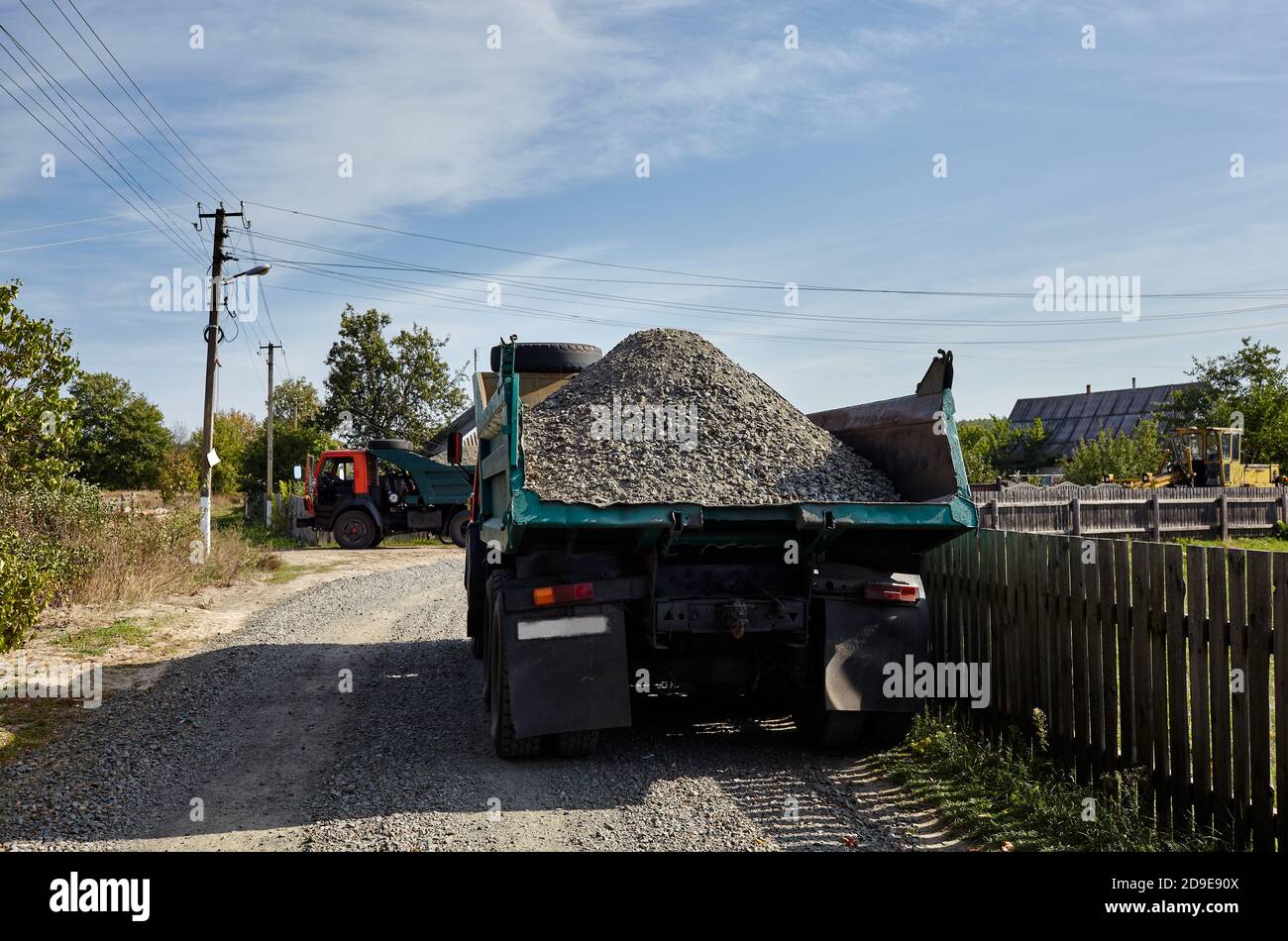 Big dump truck on suburban street, rear view. Waiting for dumping gravel for building and reconstruction roadway. Stock Photo