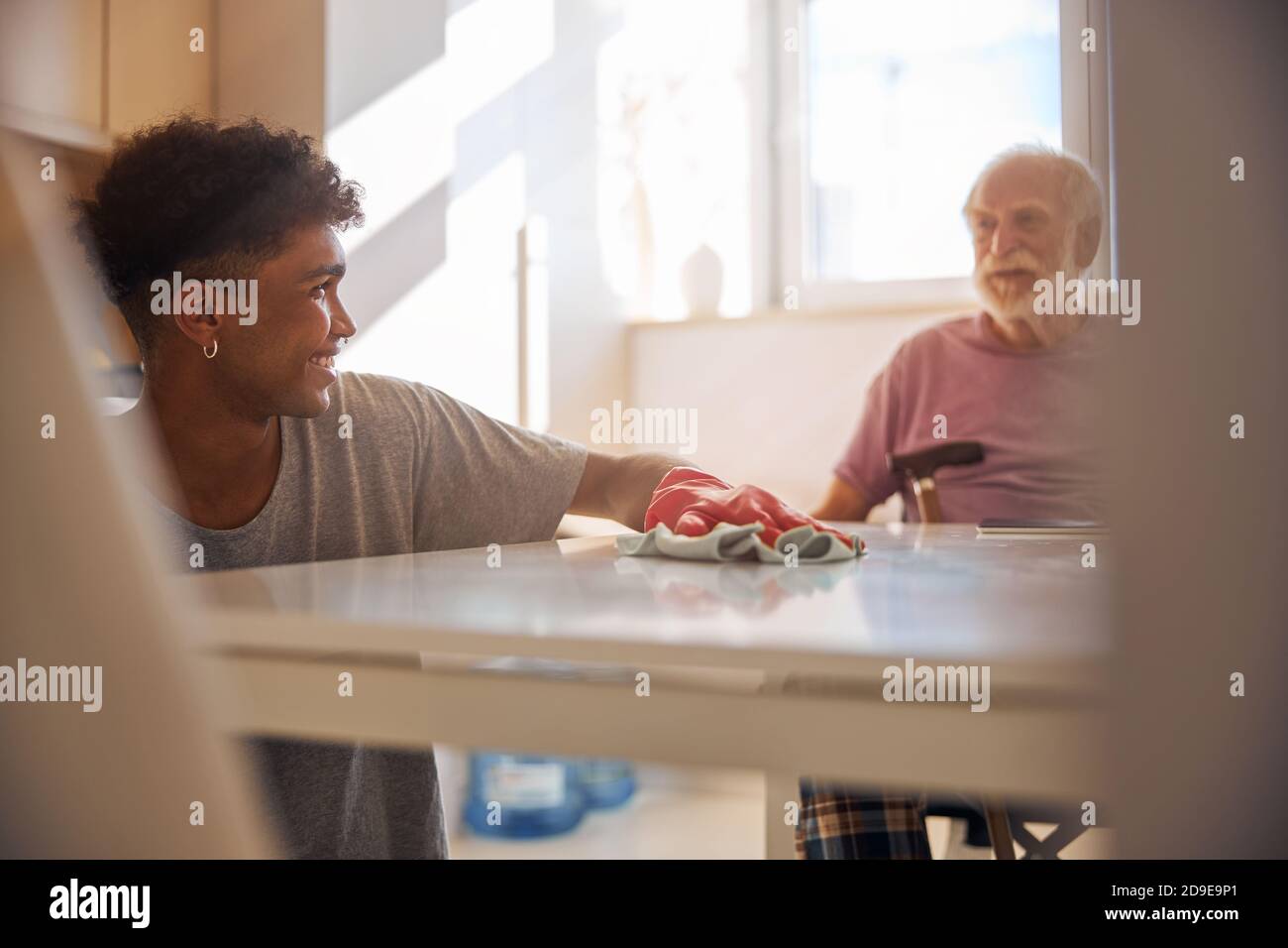 Dark-haired volunteer cleaning the disabled man kitchen Stock Photo