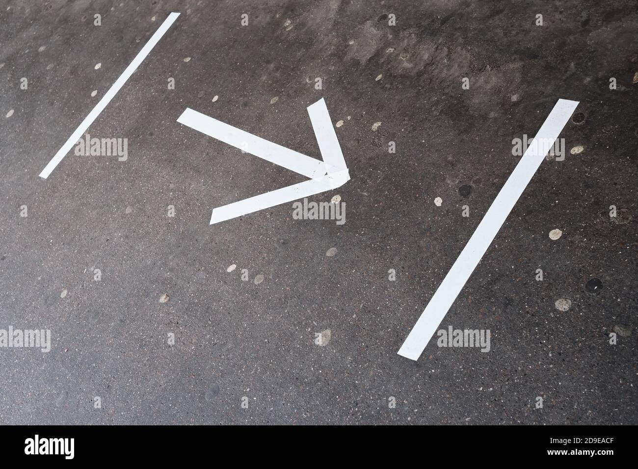 Arrow with distance markings on an asphalt surface due to risk of infection with Covid-19. Stock Photo